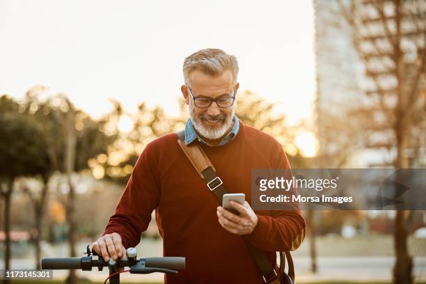 happy man with mobile phone and bicycle in city - mature men imagens e fotografias de stock