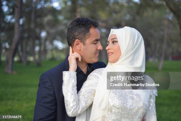 portrait of muslim bride and groom couple in love looking at each other with happy facial expression in a public park - muslim wedding stock pictures, royalty-free photos & images