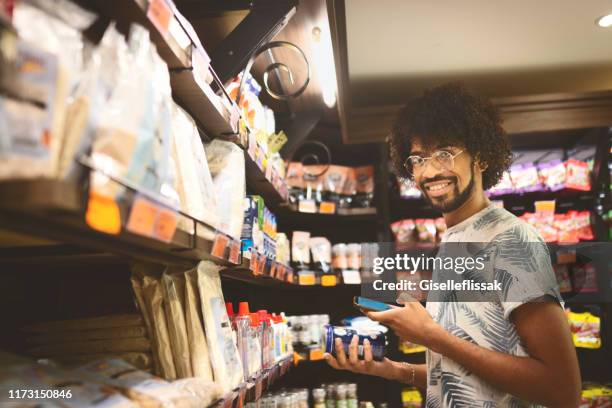 junger mann beim einkaufen im supermarkt - megastore stock-fotos und bilder