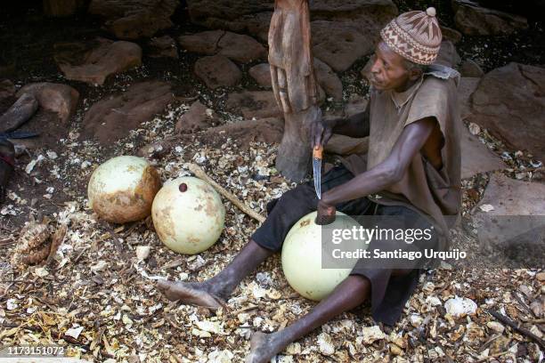 dogon man hollowing out a gourd with a knife - nombori stock pictures, royalty-free photos & images