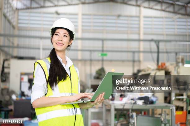 female industrial engineer in the hard hat uses laptop computer while standing in the heavy industry manufacturing factory - engineer gearwheel factory stockfoto's en -beelden