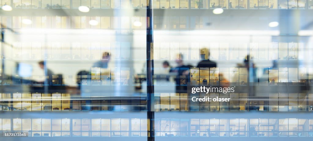 Lavoratori che lavorano fino a tardi. Edificio alto riflesso
