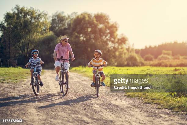 großvater fährt mit seinen enkeln fahrrad. - fahrrad fahren großeltern mit kind stock-fotos und bilder