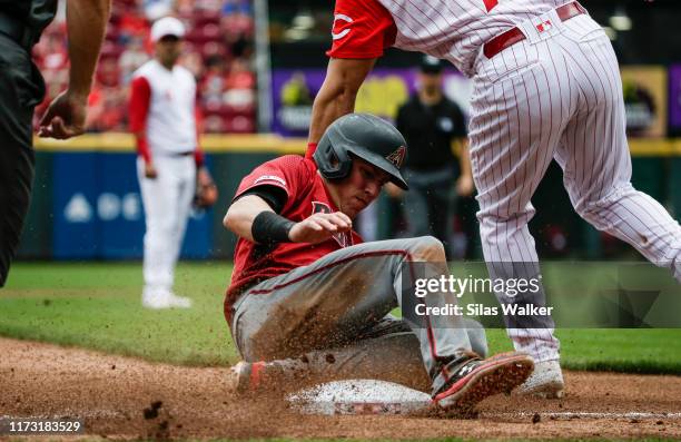 Jake Lamb of the Arizona Diamondbacks slides into third base as Eugenio Suarez of the Cincinnati Reds attempts to tag at Great American Ball Park on...