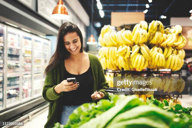 junge frau beim einkaufen in einem supermarkt - lady groceries phone stock-fotos und bilder