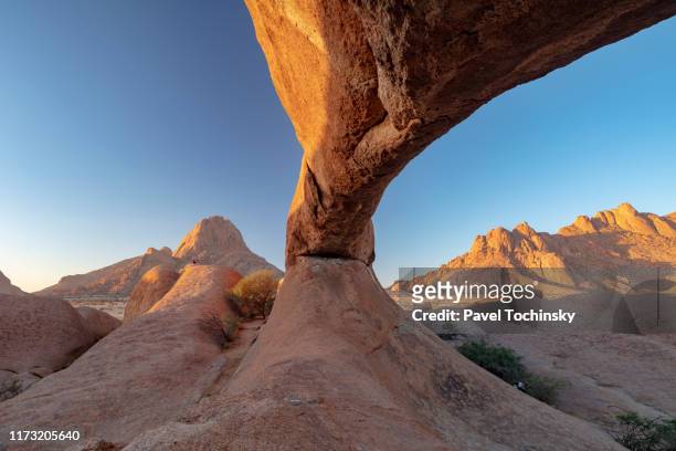 natural arch in the spitzkoppe nature reserve at sunset with spitzkoppe on the left and pontok mountains on the right, namibia, 2018 - namib desert stock pictures, royalty-free photos & images