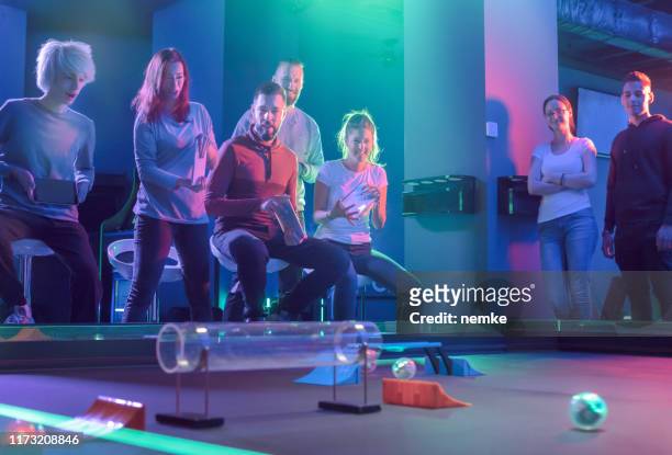 freunde spielen mit infrarot ball chasing roboter in deramüsement arcade - gruppe springen ipad stock-fotos und bilder