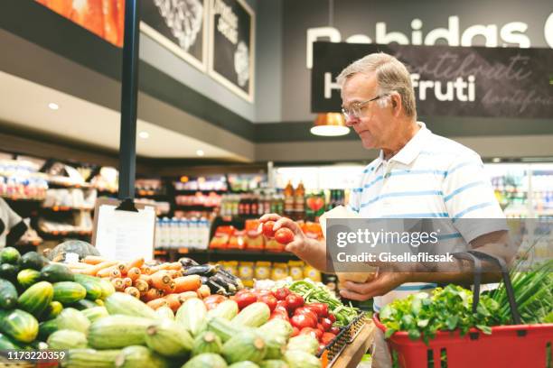 homme aîné faisant des emplettes dans un supermarché achetant des légumes - produce aisle photos et images de collection