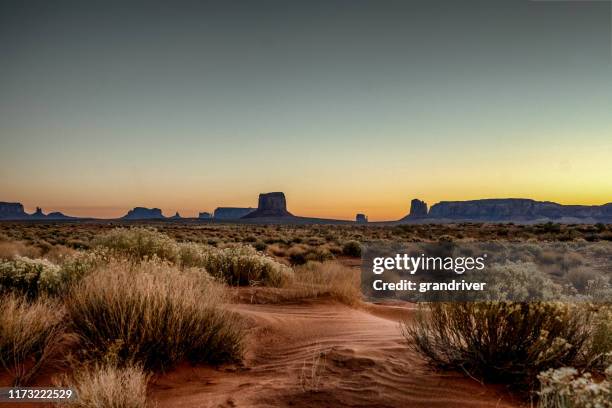 dawn at monument valley tribal park met prachtig woestijn zand voor de majestueuze mitten bluffs van het tribal park - het zuidwesten van de verenigde staten stockfoto's en -beelden