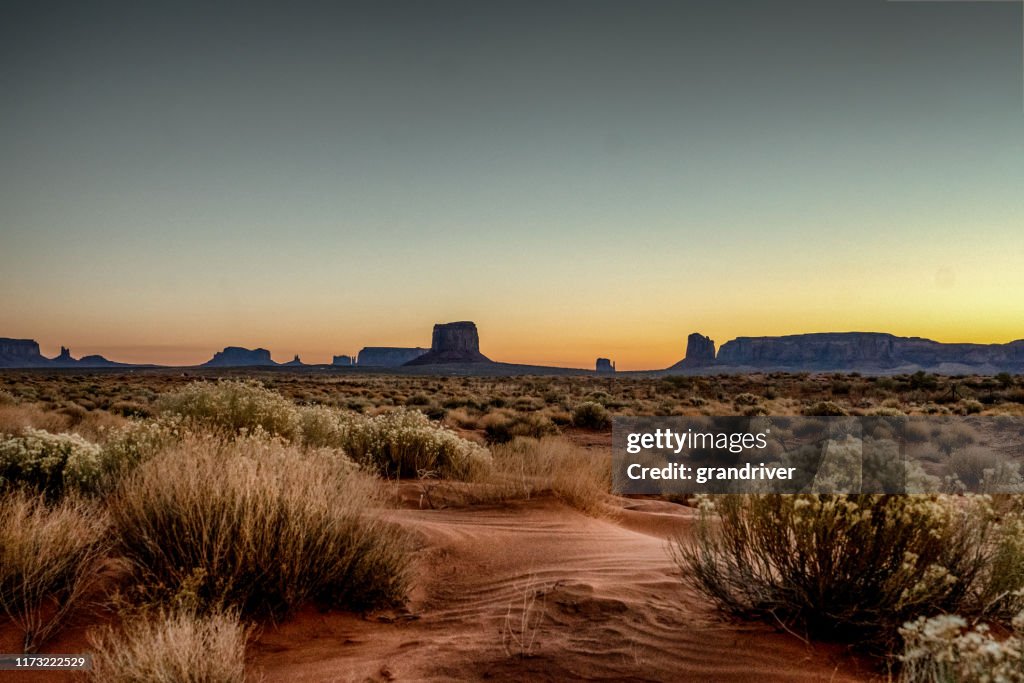 Gryning på Monument Valley Tribal Park med vacker ökensand framför den majestätiska mitten Bluffs av Tribal Park