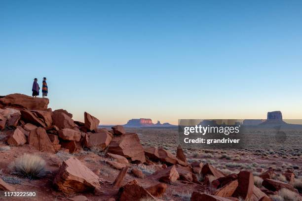 irmã indiana do navajo do nativo americano de dois adolescentes na roupa tradicional que aprecia o deserto vasto e a paisagem vermelha da rocha no parque tribal famoso do navajo no arizona do vale do monumento no alvorecer - etnia cheroqui - fotografias e filmes do acervo