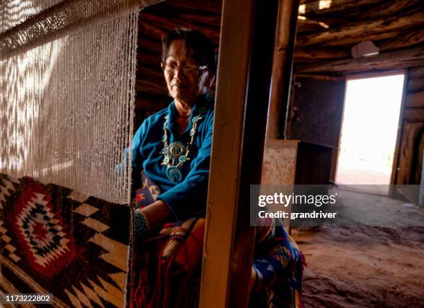 native american navajo woman in an authentic hogan weaving a traditional blanket on a loom - cherokee stock pictures, royalty-free photos & images