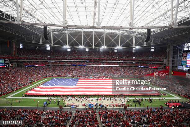 The United States flag is held on the field for the national anthem before the NFL game between the Arizona Cardinals and the Detroit Lions at State...