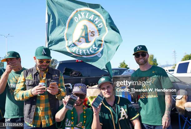 Oakland Athletics fans tailgating and showing their tickets on their phones in the parking lot prior to the start of the American League WildCard...