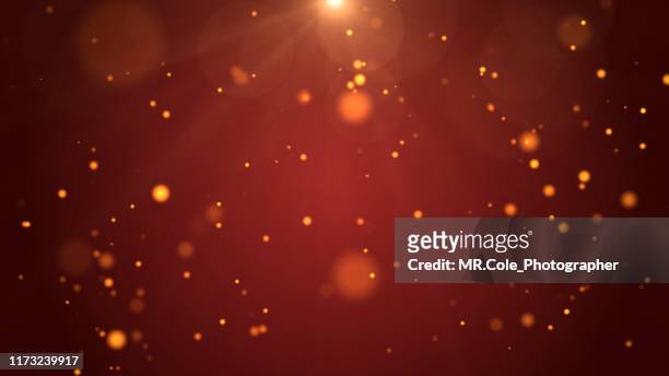 christmas background, de-focused gold colored particles on red background with lens flare - glamour stock-fotos und bilder
