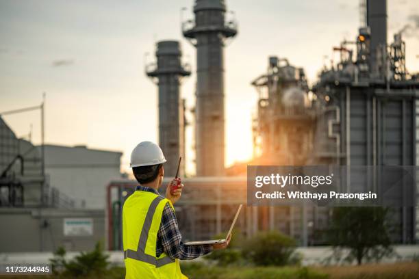 manager engineering in standard safety uniform working in gas turbine electric power plant during sunset or morning time background - gas plant sunset stock-fotos und bilder