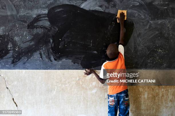 Young boy cleans the blackboard on the first day of school in Segou on October 1, 2019. - In central Mali, in the heart of Sahel bogged down in a...