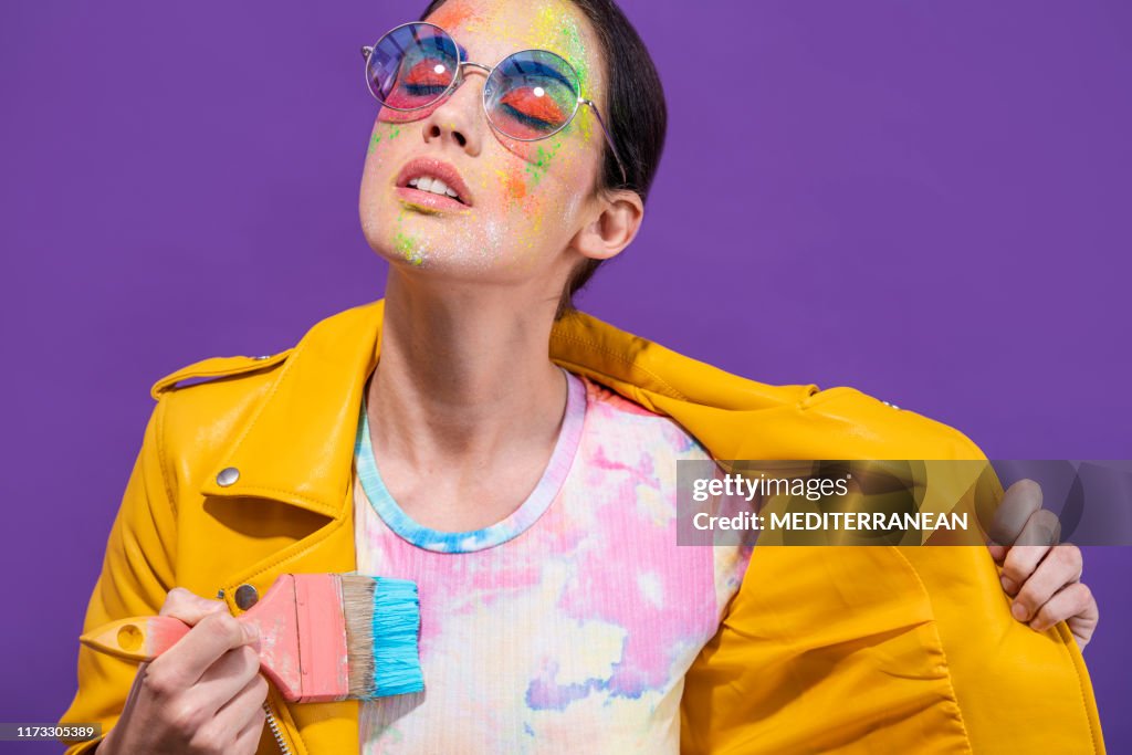 Fashion artist painter girl with brush painting herself t-shirt on purple