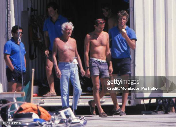 Italian entrepreneur Gianni Agnelli bare-chested beside another bare-chested man. 1990s