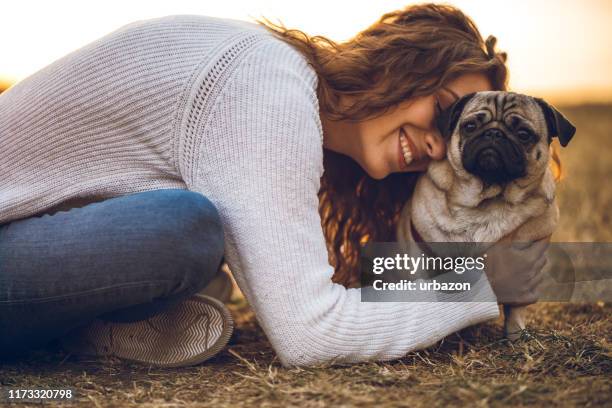woman hugging with pug in a park - pug stock pictures, royalty-free photos & images