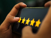 attractive hands showing five stars rating on a smart phone