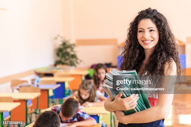 beautiful teacher holding textbooks - teacher with folder stock pictures, royalty-free photos & images