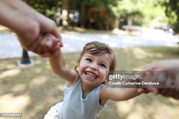 a 3 years old boy having fun in the arms of his mum - children playing outside stock-fotos und bilder