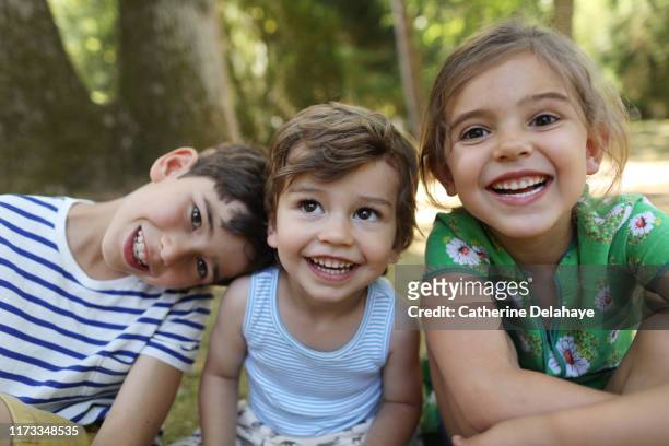 3 brothers and sister posing together in the garden - garden of laughs stockfoto's en -beelden