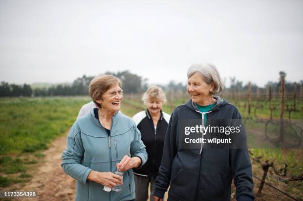 active seniors women walking for exercise outdoors talking together waist up - grandmother walking stock pictures, royalty-free photos & images