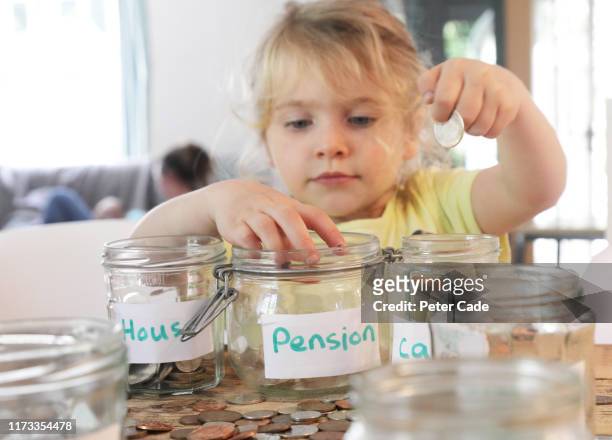 young girl putting money into savings jars - kids saving money stock pictures, royalty-free photos & images