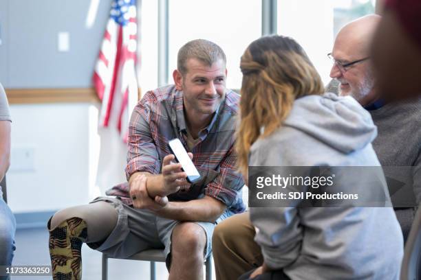 wounded veteran shows something on smartphone to friends - wounded vet stock pictures, royalty-free photos & images