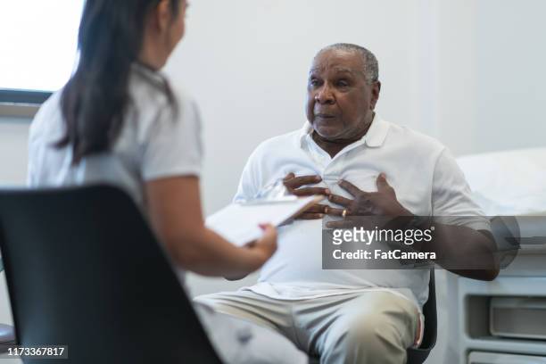 senior adult man in consultation with female doctor - male chest stock pictures, royalty-free photos & images