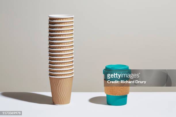a stack of disposable coffee cups next to a reusable coffee cup - coffee take away cup simple stock pictures, royalty-free photos & images