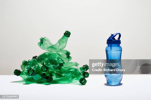 a heap of disposable water bottles next to a reusable water bottle - bouteille d'eau photos et images de collection