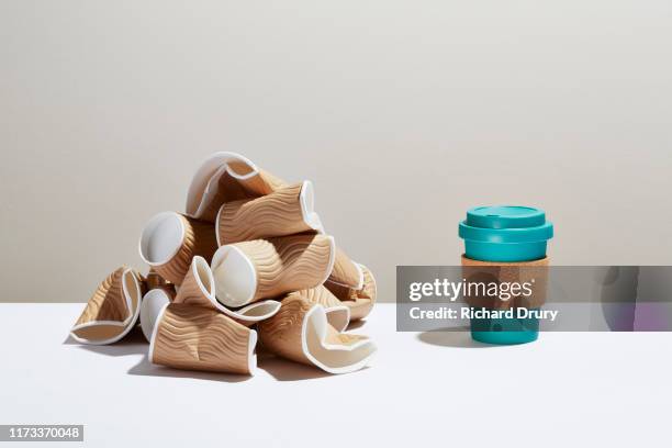 a pile of disposable coffee cups next to a reusable coffee cup - plastic cup stock pictures, royalty-free photos & images