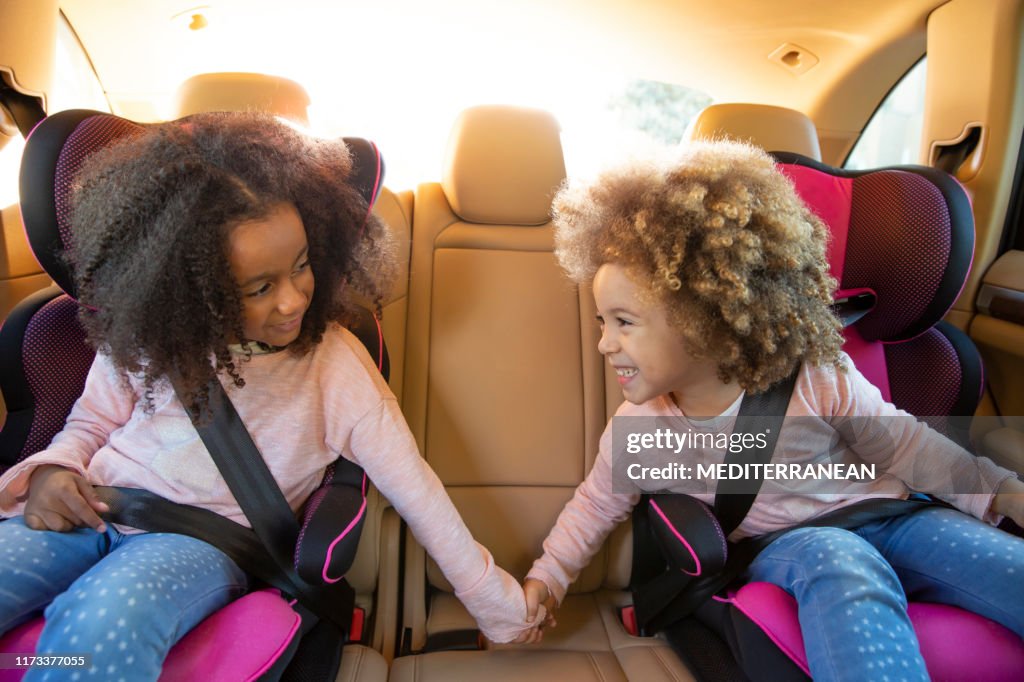 Ethnic sister girls car back seat with belts