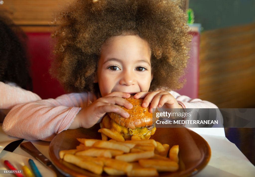 Ethnic kid girl eating burger and chips