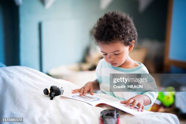 cute little boy reading book at home - 2 year old book stock pictures, royalty-free photos & images