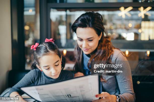 mother and daughter in restaurant - menu imagens e fotografias de stock