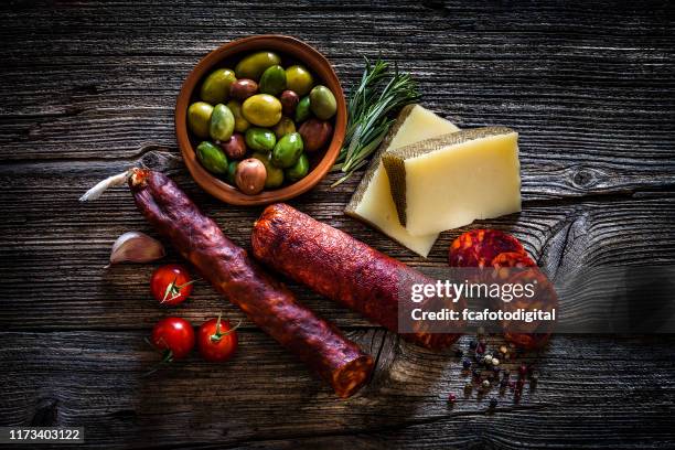 spanish food: manchego cheese, chorizo and olives on rustic wooden table - chorizo stock pictures, royalty-free photos & images