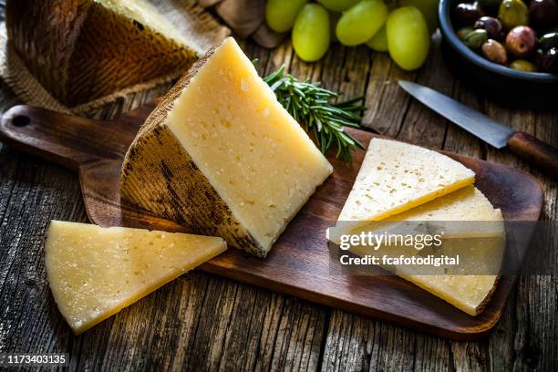 cibo spagnolo: formaggio manchego su tavolo rustico in legno - cheese slice foto e immagini stock