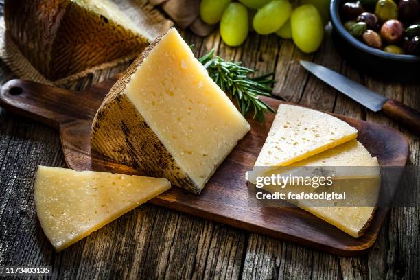 spanish food: manchego cheese on rustic wooden table - manchego stock pictures, royalty-free photos & images