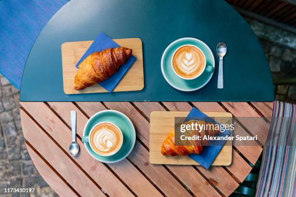 directly above view of two croissants and cappuccino cups - foodstyling stock-fotos und bilder