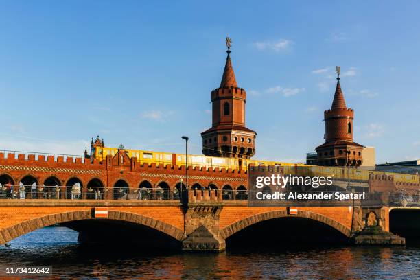 oberbaum bridge (oberbraumbrücke) and yellow metro train on a sunny day with blue sky, berlin, germany - berlin friedrichshain stockfoto's en -beelden