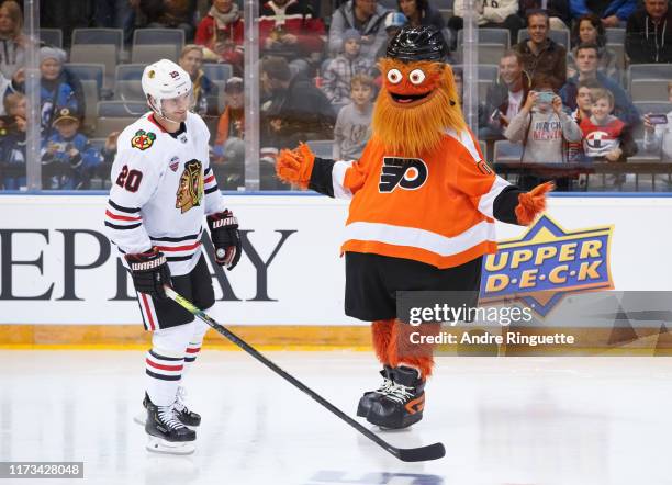 Philadelphia Flyers mascot Gritty jokes with Brandon Saad of the Chicago Blackhawks during a skills competition before the Global Series Challenge...