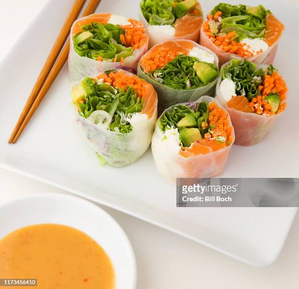 salmon spring rolls on a plate with a small dish of dipping sauce and chopsticks - goi cuon stock pictures, royalty-free photos & images