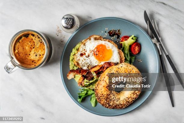 bagel sandwich with avocado, fried egg and side salad on white background - avocado toast white background stockfoto's en -beelden