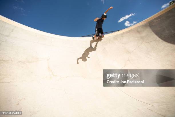 a skateboarder carving a turn in a deep concrete bowl - skatepark stock-fotos und bilder