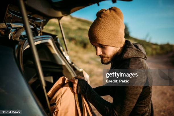 man unloading the car trunk packed with luggage for road trip - car camping luggage imagens e fotografias de stock