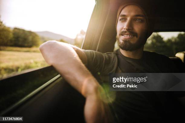 hipster man genieten van de rit op de achterbank in de auto - car interior sunset stockfoto's en -beelden